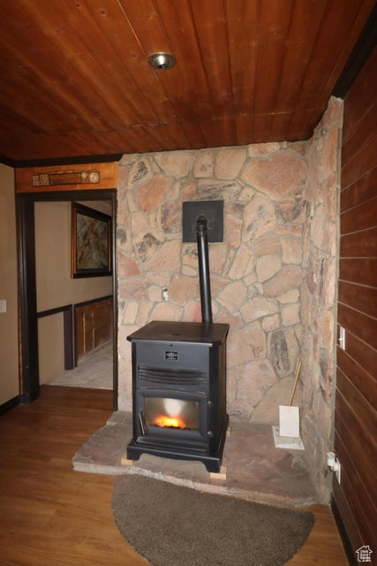 Interior details with a wood stove, wooden ceiling, and wood finished floors