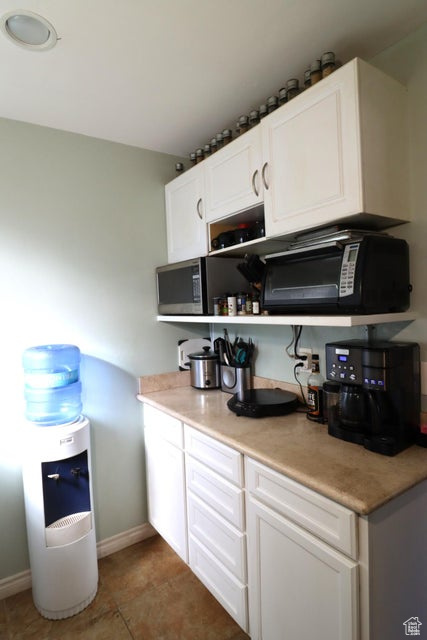 Kitchen with white cabinetry, black microwave, and baseboards