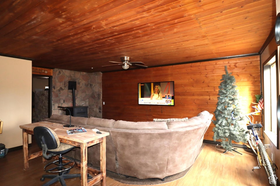 Living area with a wood stove, wood ceiling, a ceiling fan, and wood finished floors