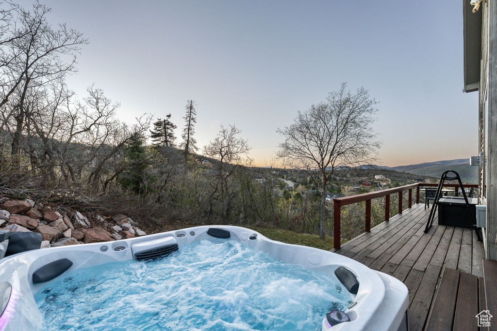 Deck at dusk featuring an outdoor hot tub