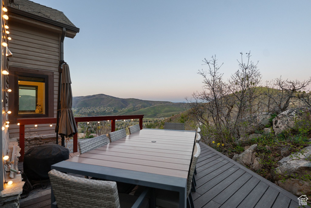 Wooden deck featuring a grill, outdoor dining area, and a mountain view
