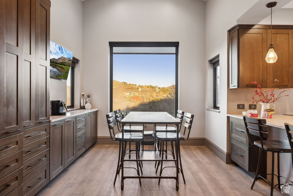 Dining room with baseboards, light wood-type flooring, and a towering ceiling