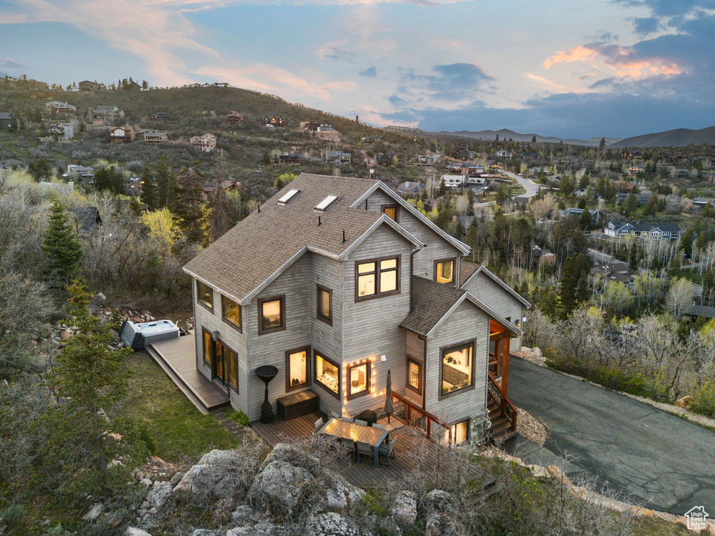 View of front facade with a deck with mountain view, aphalt driveway, and a shingled roof