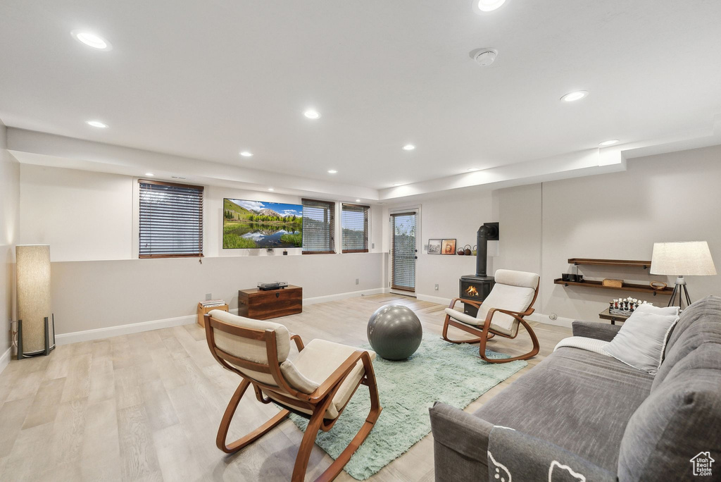 Living area with a wood stove, light wood-style flooring, baseboards, and recessed lighting