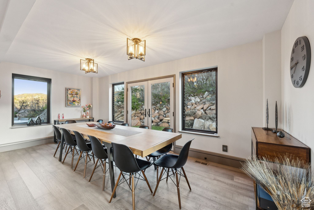 Dining space featuring a chandelier, light wood finished floors, french doors, and baseboards