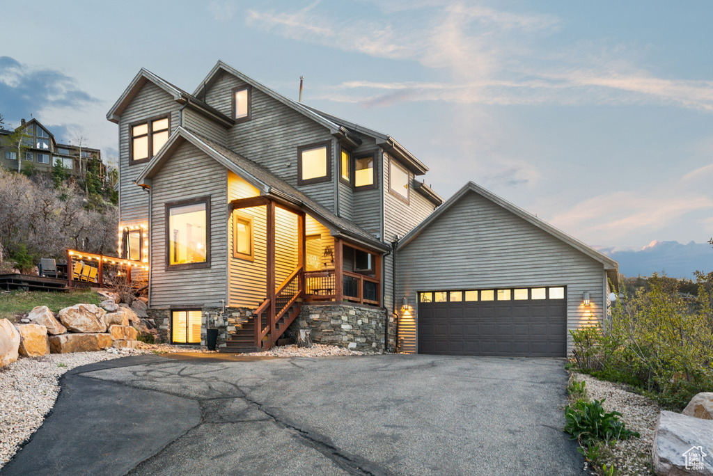 View of front facade featuring stairs, driveway, and an attached garage