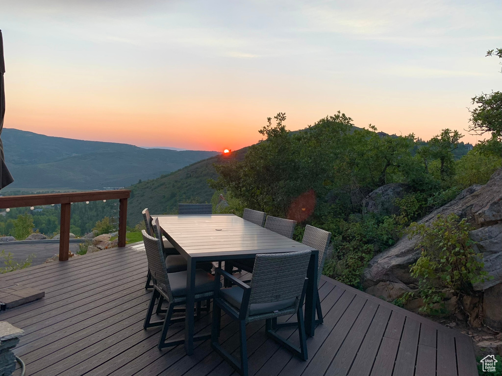 Deck at dusk featuring outdoor dining area and a mountain view