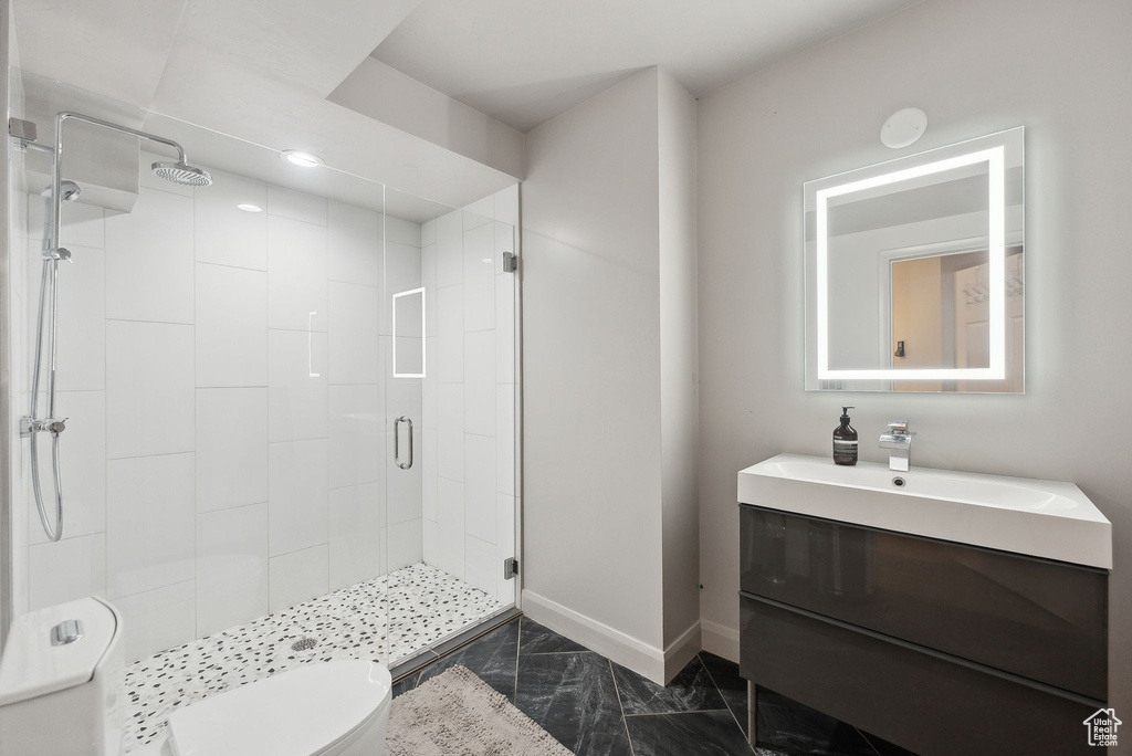 Full bath featuring a stall shower, toilet, marble finish floor, baseboards, and vanity