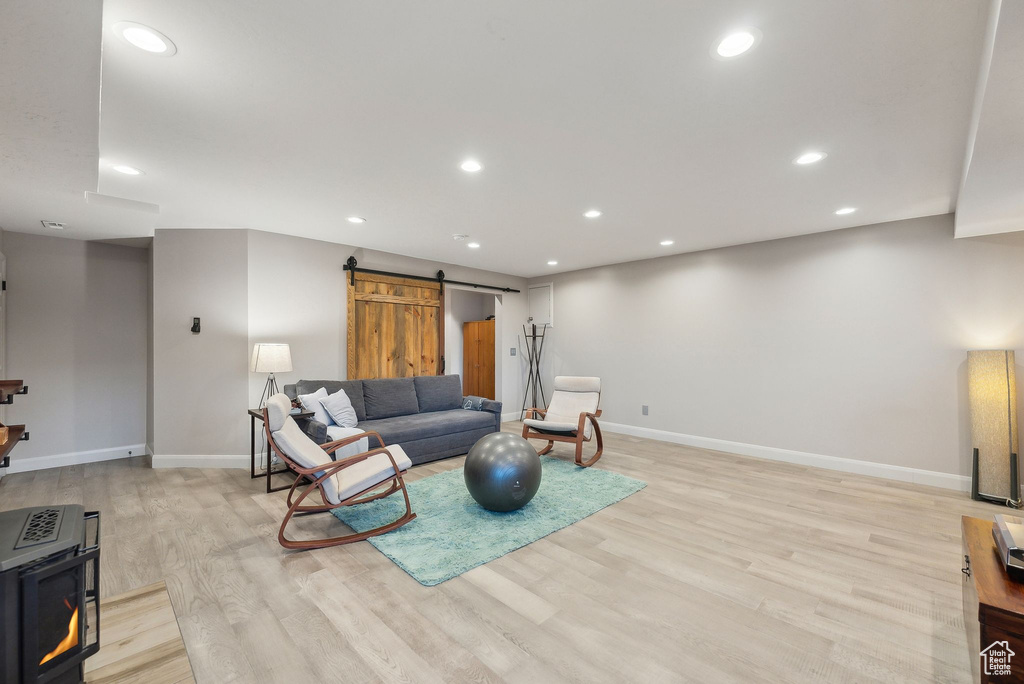 Living room featuring baseboards, recessed lighting, light wood-style flooring, and a barn door