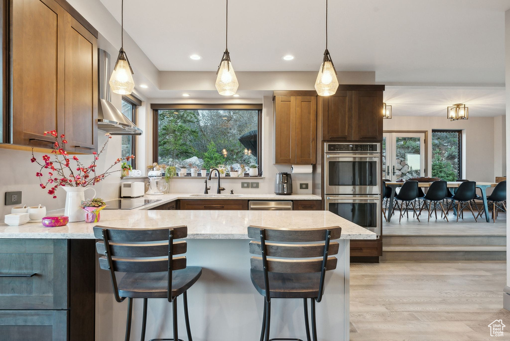 Kitchen with light stone counters, a peninsula, appliances with stainless steel finishes, and a sink