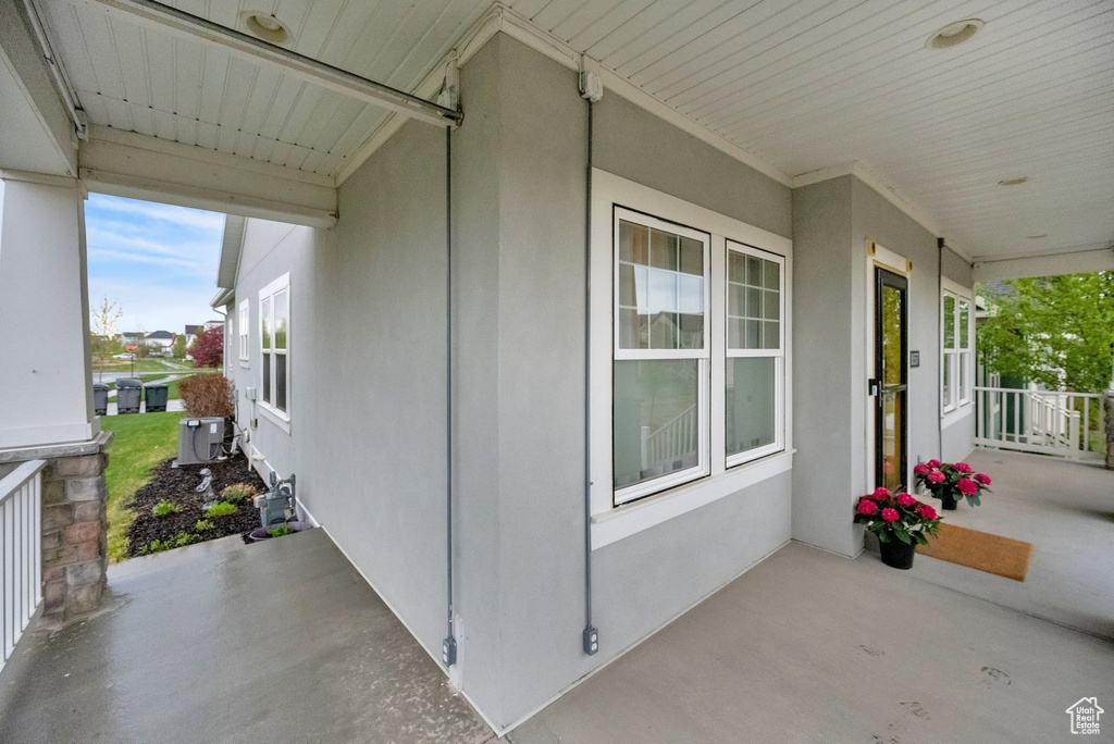 View of property exterior featuring stucco siding, covered porch, and cooling unit