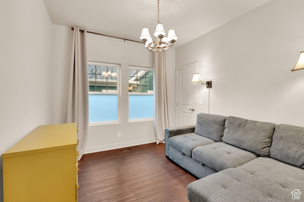 Living area with dark wood-type flooring, baseboards, and a chandelier