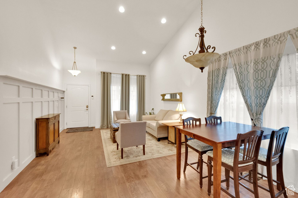 Dining area with light wood-style floors, high vaulted ceiling, and recessed lighting