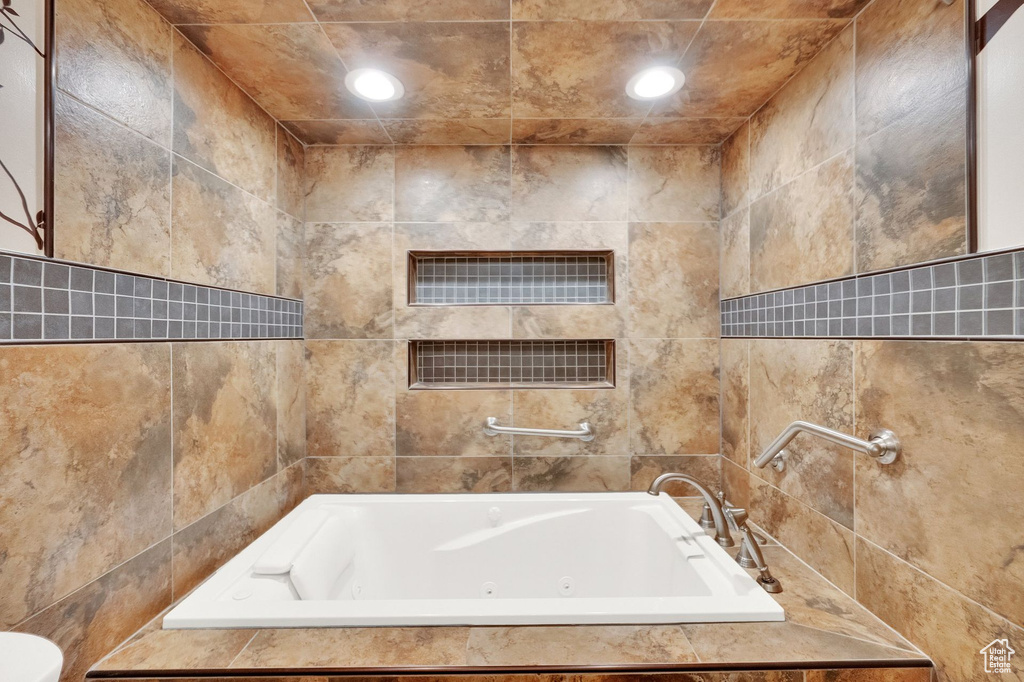 Bathroom with recessed lighting, tile walls, and a tub with jets