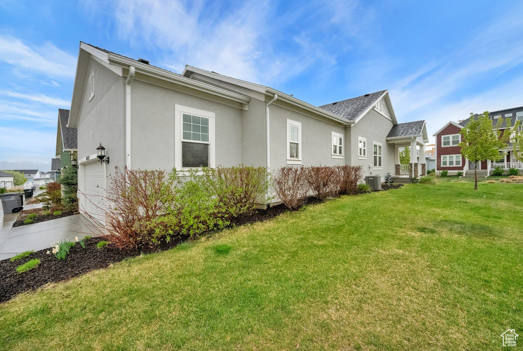 Rear view of property with a garage, cooling unit, stucco siding, a yard, and a residential view