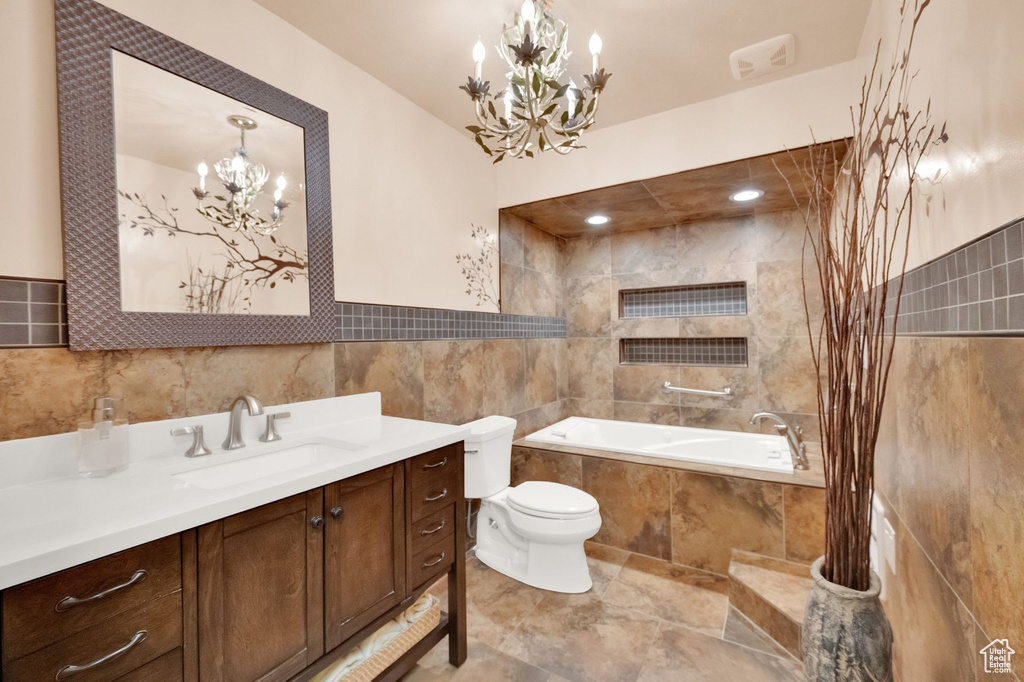 Full bathroom with visible vents, tile walls, vanity, toilet, and a chandelier