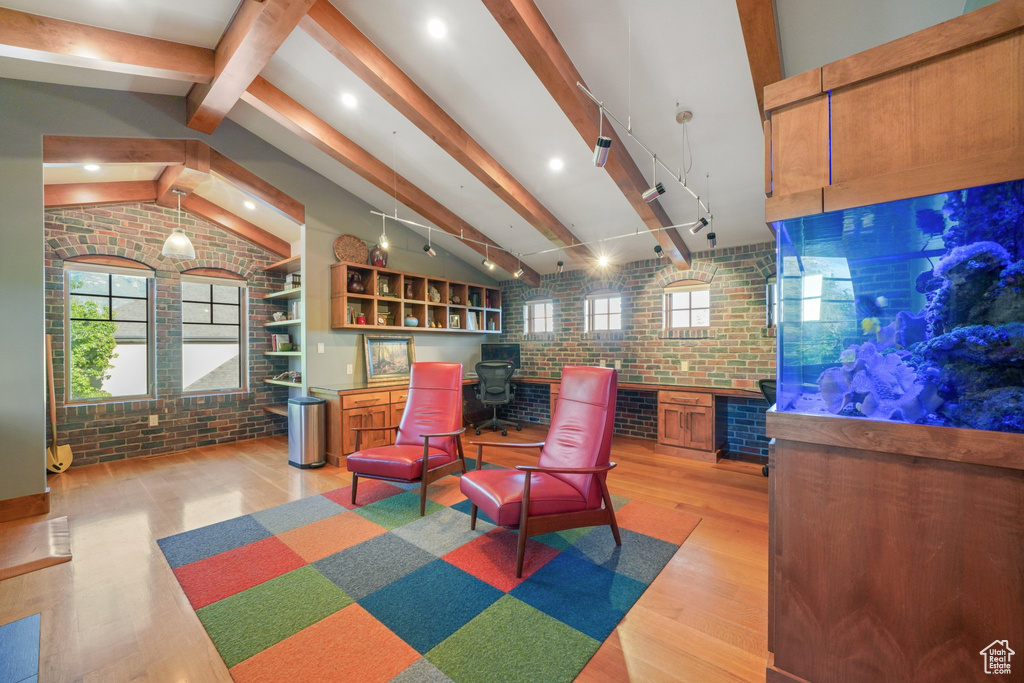 Sitting room featuring brick wall, light wood-style floors, plenty of natural light, and rail lighting