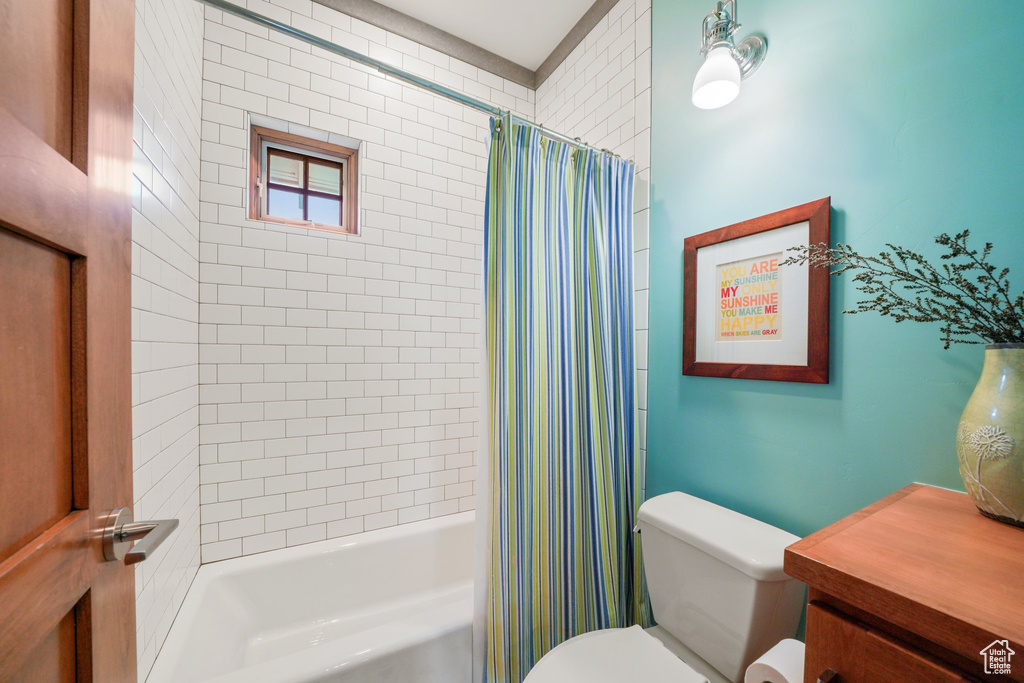 Bathroom featuring toilet and shower / bathtub combination with curtain