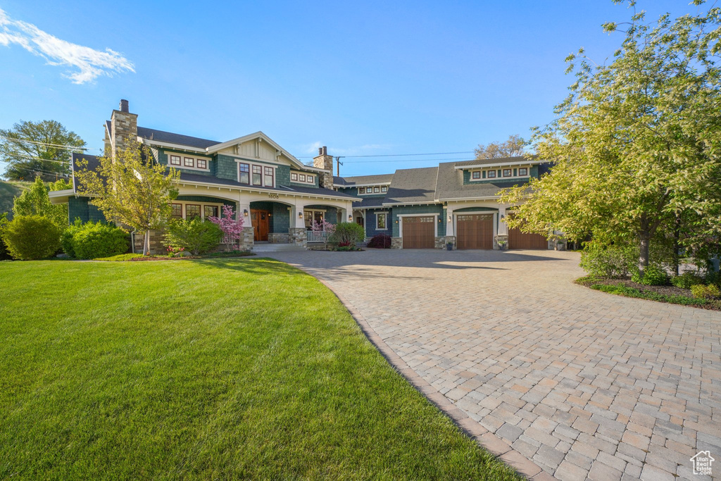 View of front facade with decorative driveway, a front lawn, and a chimney