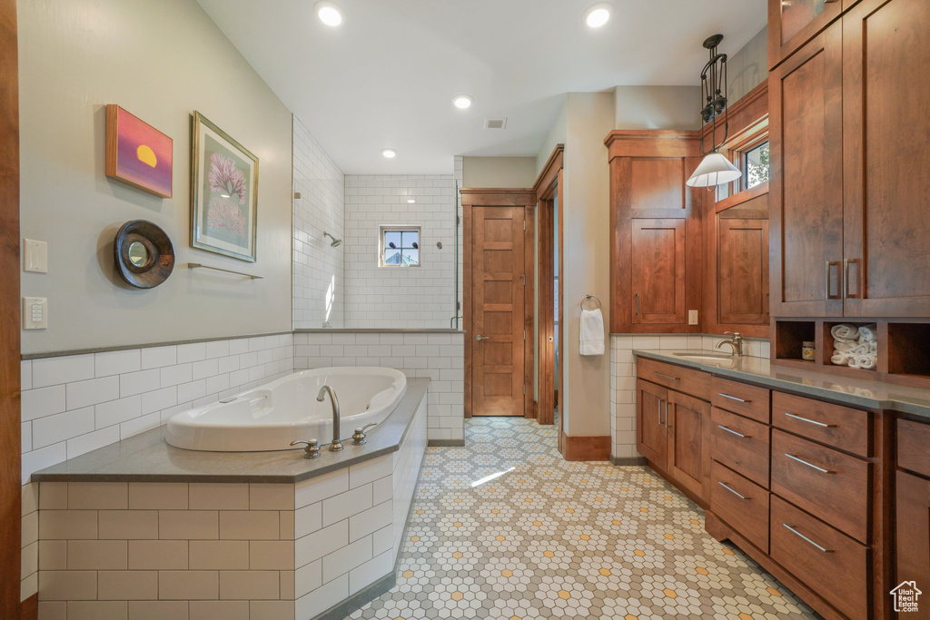 Bathroom featuring a bath, vanity, tile patterned floors, and tiled shower
