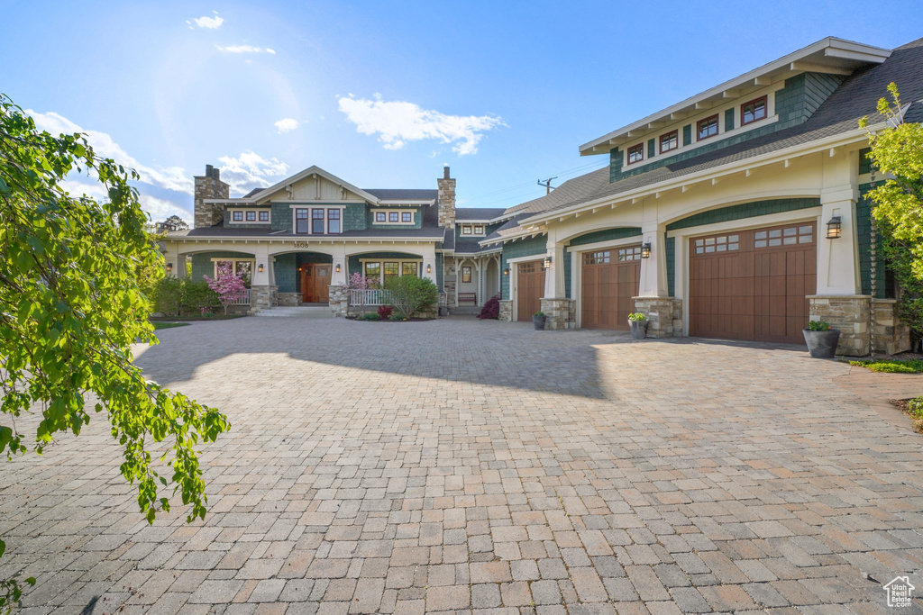 Craftsman inspired home featuring stone siding, decorative driveway, and an attached garage