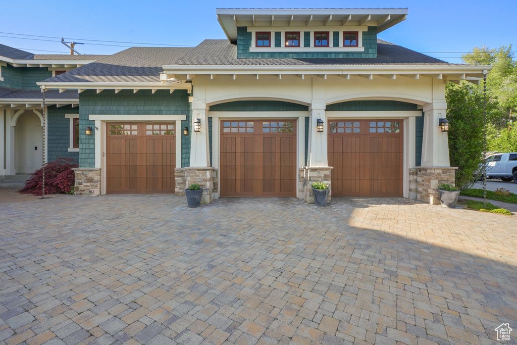 View of front of home with a garage, decorative driveway, and stone siding