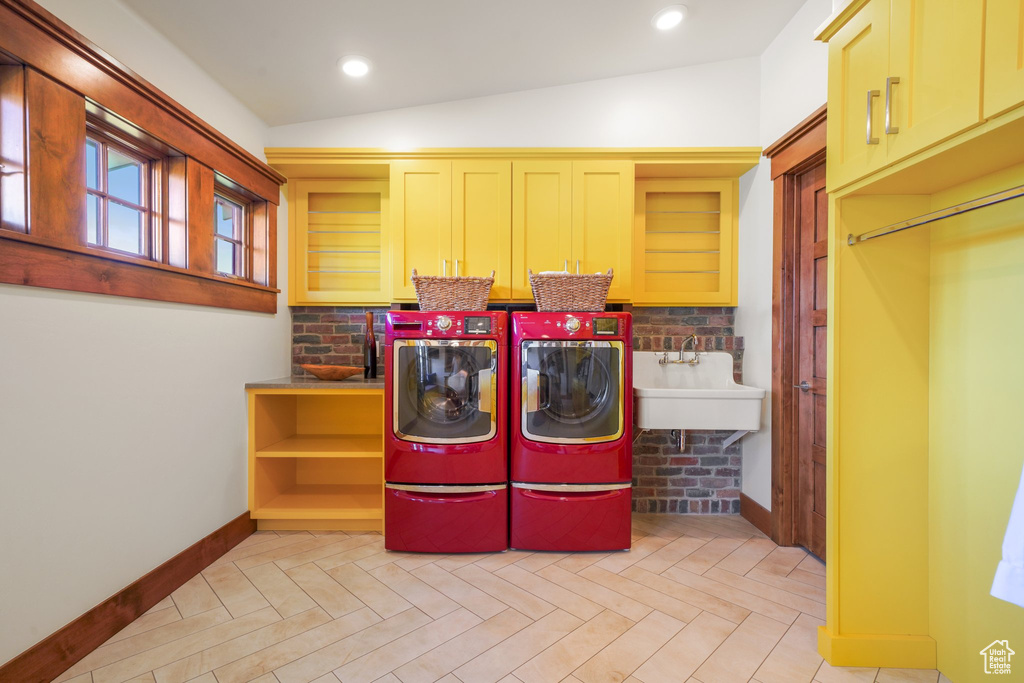 Laundry room featuring washer and clothes dryer, cabinet space, a sink, and baseboards