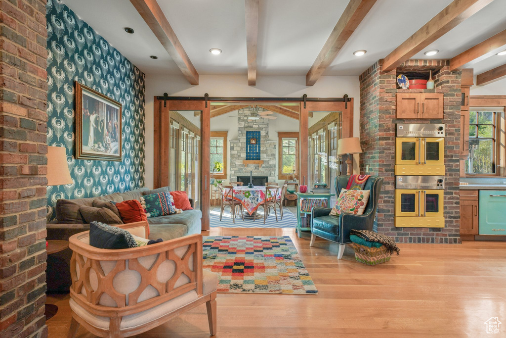 Living room with a barn door, wood finished floors, and beamed ceiling