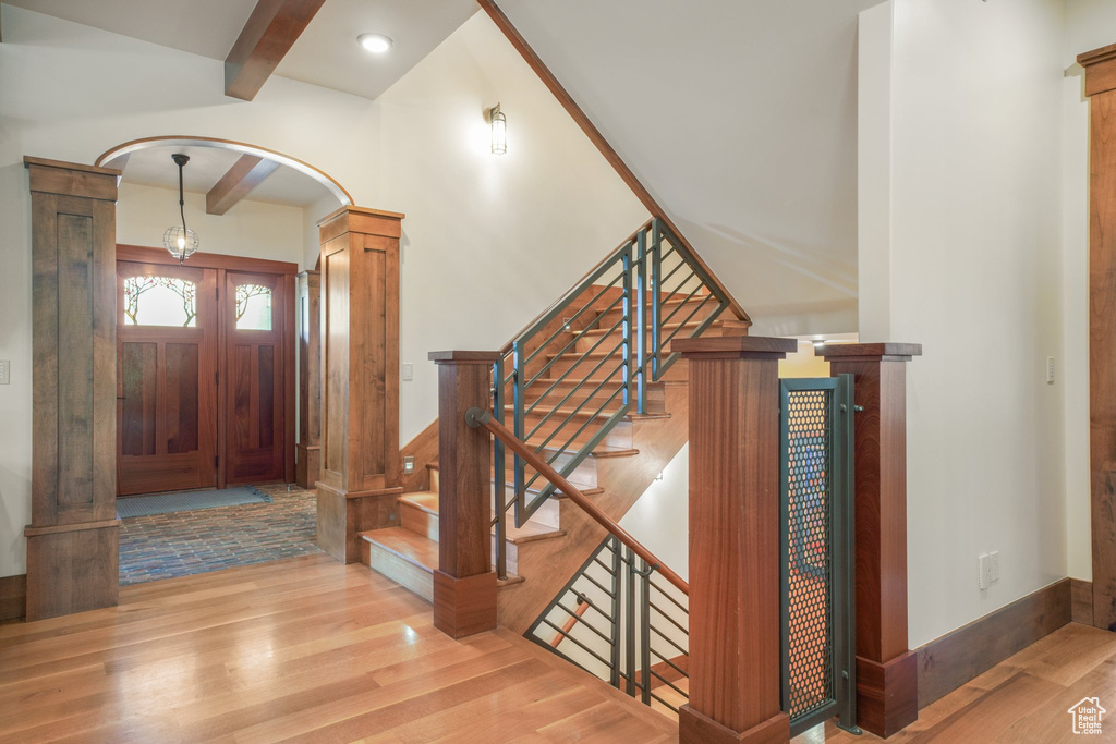 Entryway with wood finished floors, arched walkways, beam ceiling, and stairs