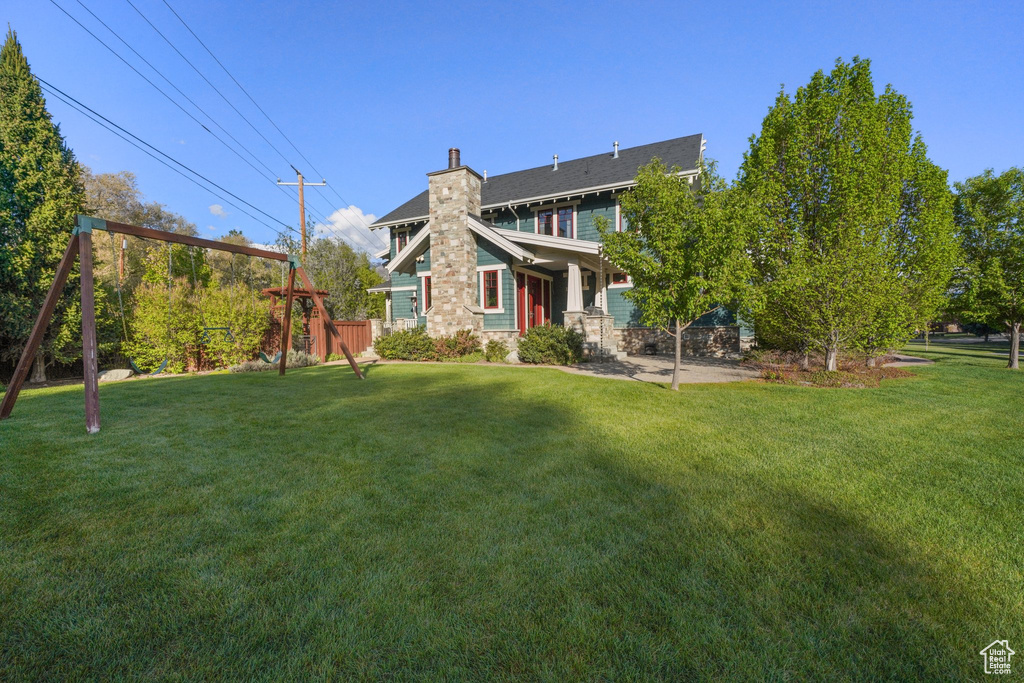 Back of property featuring a chimney, a yard, stone siding, and fence