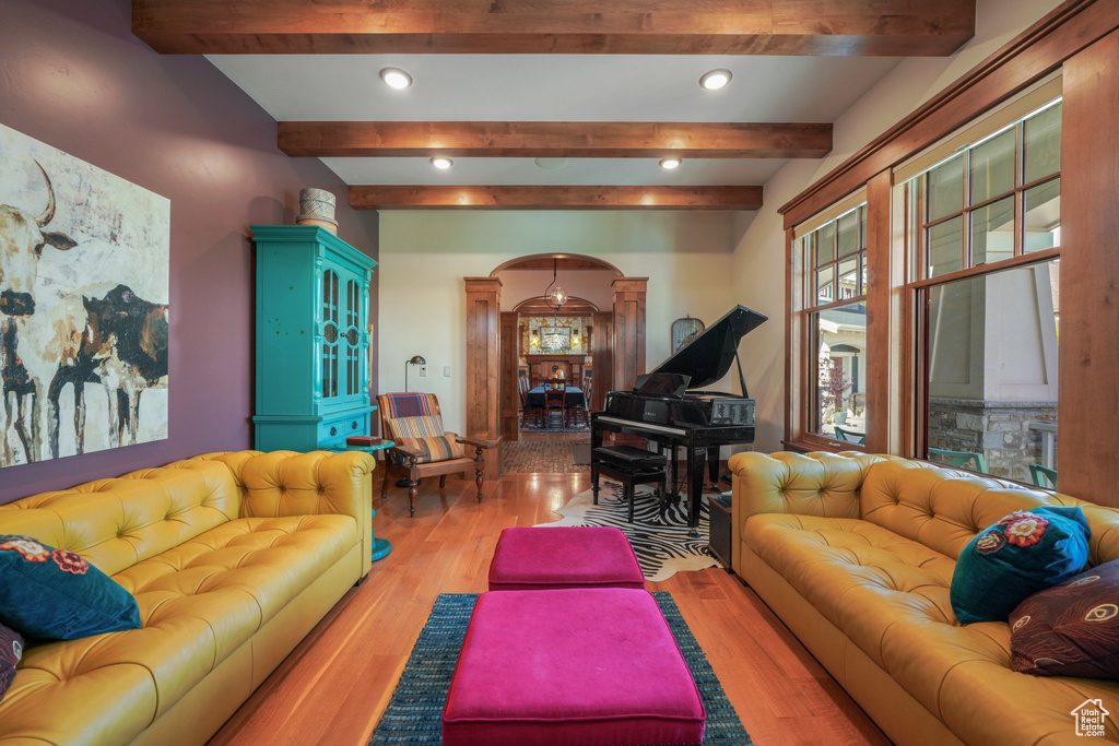 Living room with arched walkways, wood finished floors, beamed ceiling, recessed lighting, and ornate columns