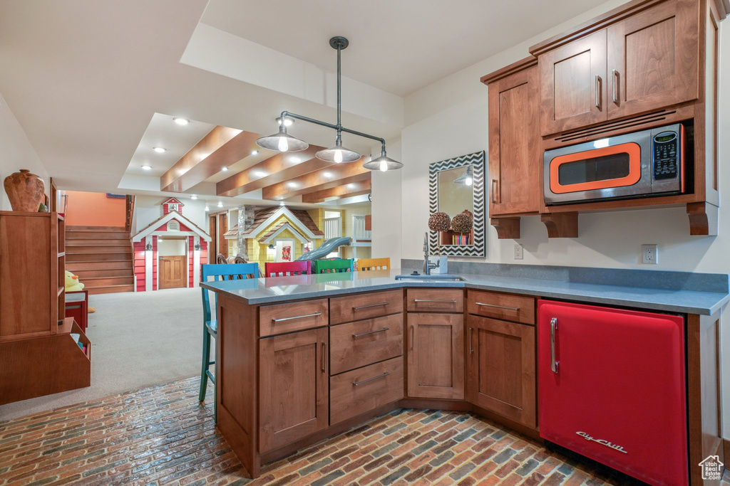 Kitchen with brick flooring, a sink, brown cabinetry, and a peninsula