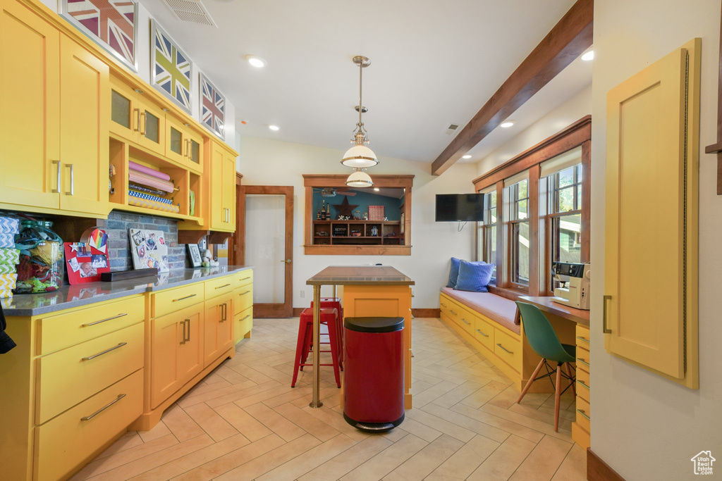 Kitchen featuring a center island, a kitchen breakfast bar, glass insert cabinets, decorative backsplash, and baseboards