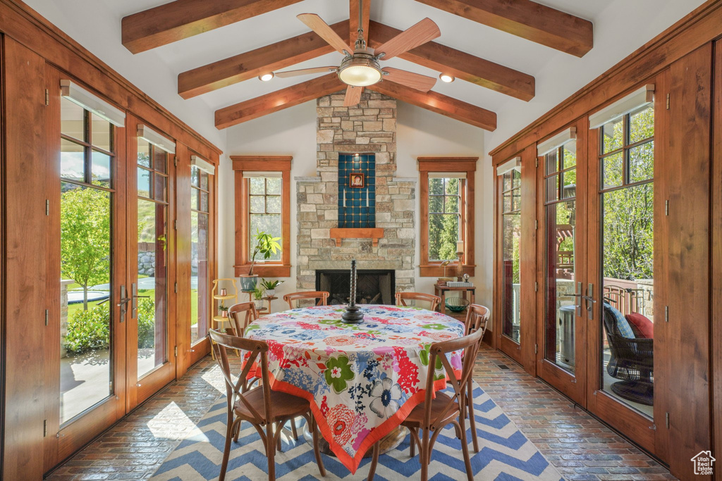 Dining space with french doors, brick floors, ceiling fan, and a fireplace