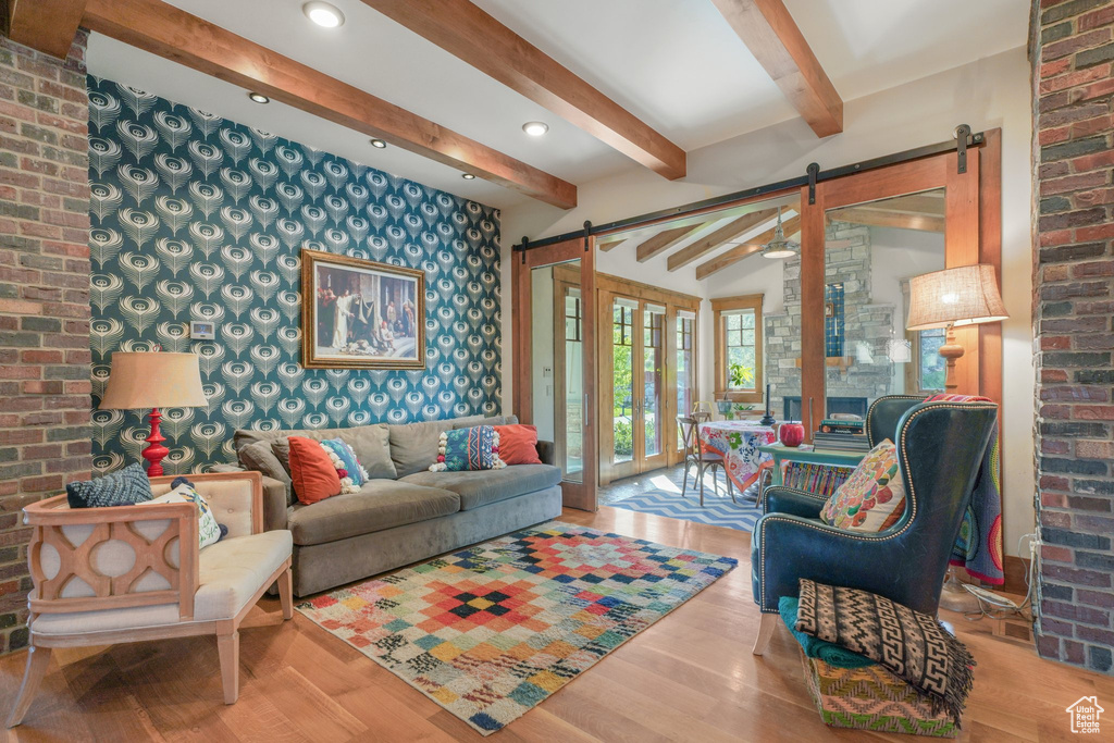 Living area featuring a barn door, wood finished floors, brick wall, recessed lighting, and wallpapered walls