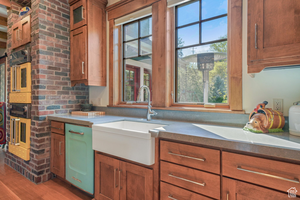 Kitchen featuring a sink, brown cabinetry, light wood finished floors, and glass insert cabinets