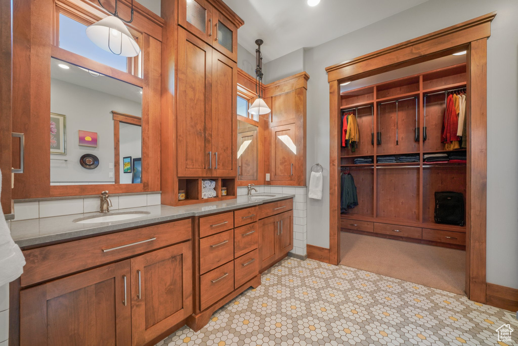 Bathroom with double vanity, a spacious closet, and baseboards