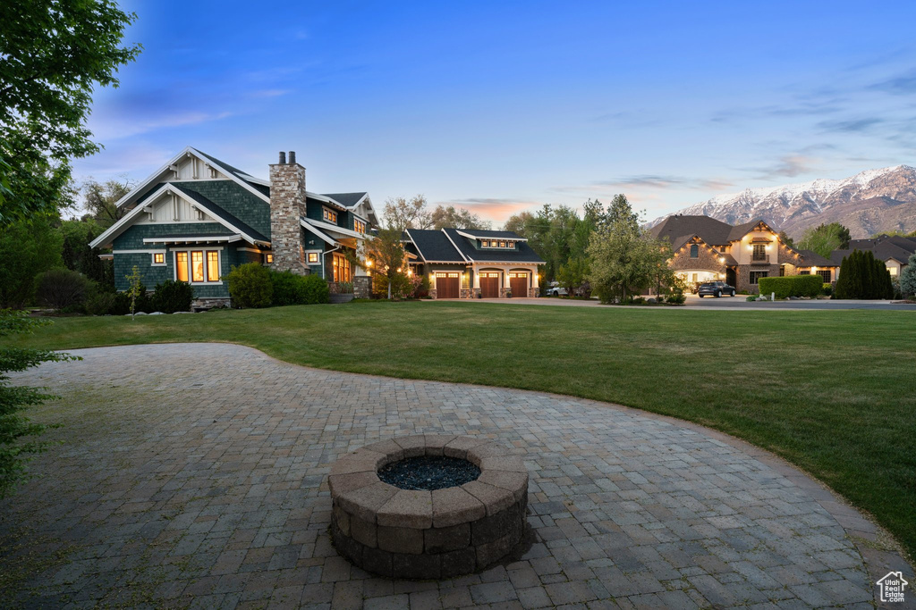 Exterior space with a chimney, a yard, solar panels, a fire pit, and curved driveway