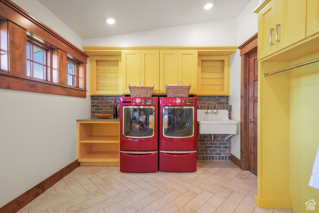 Washroom featuring washing machine and clothes dryer, baseboards, and cabinet space