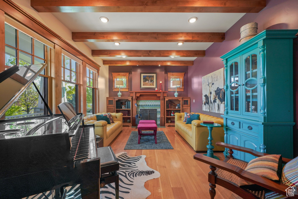 Living room with light wood finished floors, recessed lighting, beamed ceiling, and a premium fireplace