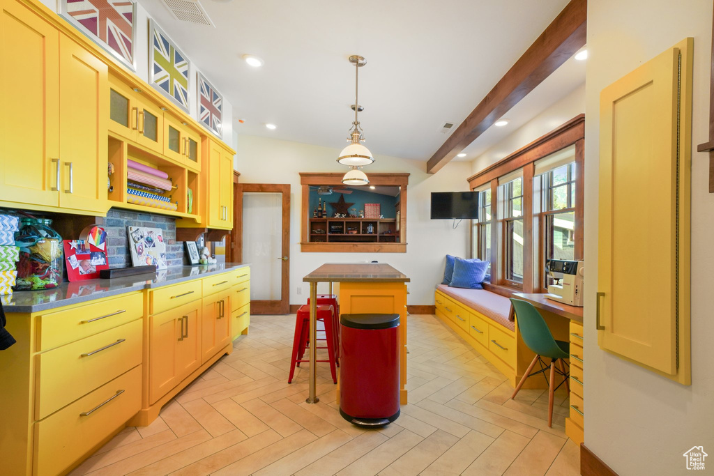 Kitchen with a kitchen breakfast bar, visible vents, a center island, glass insert cabinets, and baseboards