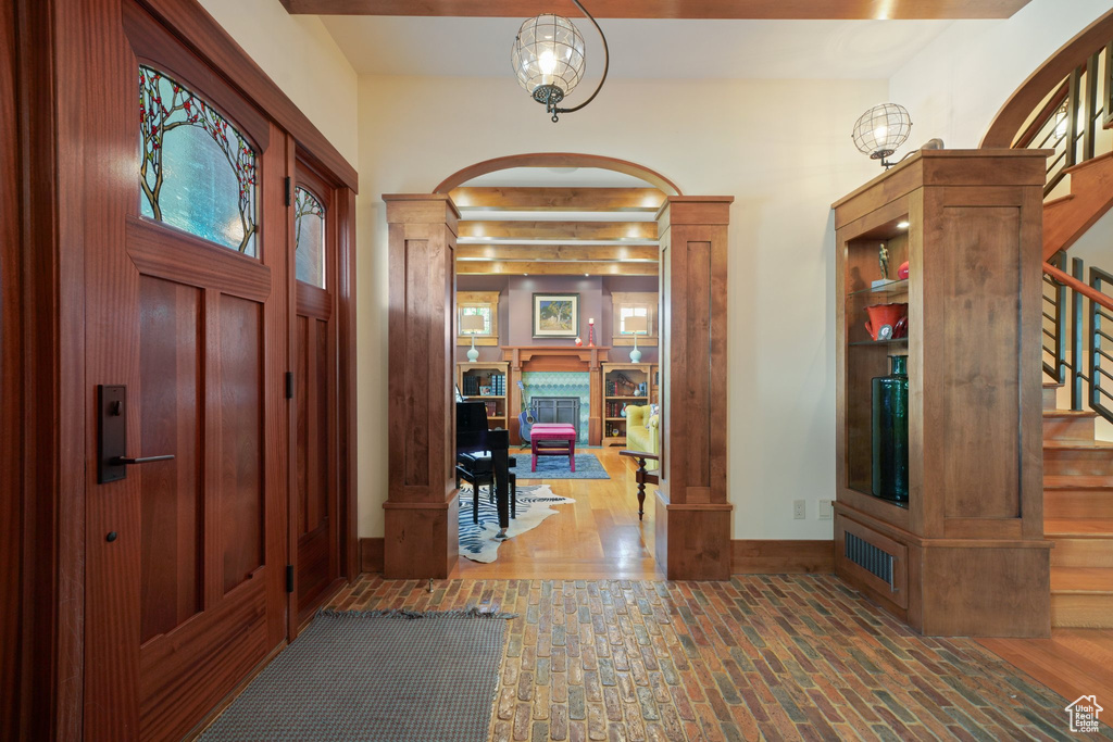 Entryway featuring arched walkways, stairs, brick flooring, ornate columns, and baseboards
