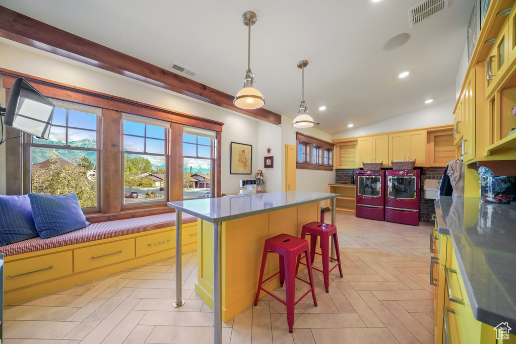 Kitchen featuring washing machine and dryer, a breakfast bar, a center island, dark countertops, and backsplash