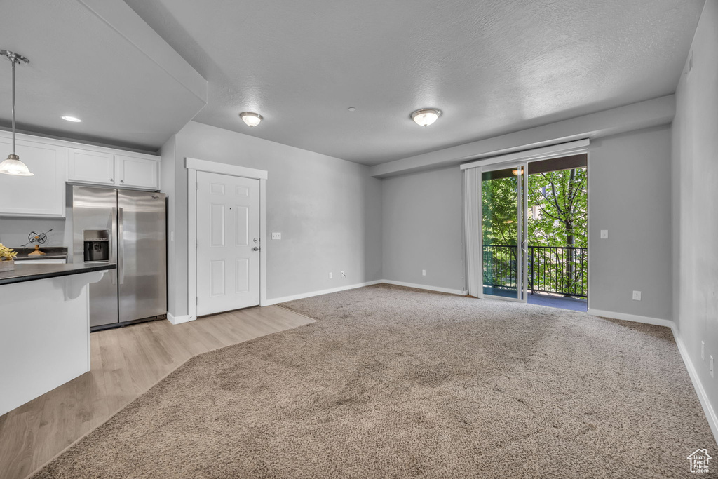Unfurnished living room featuring baseboards, light carpet, and light wood-style floors