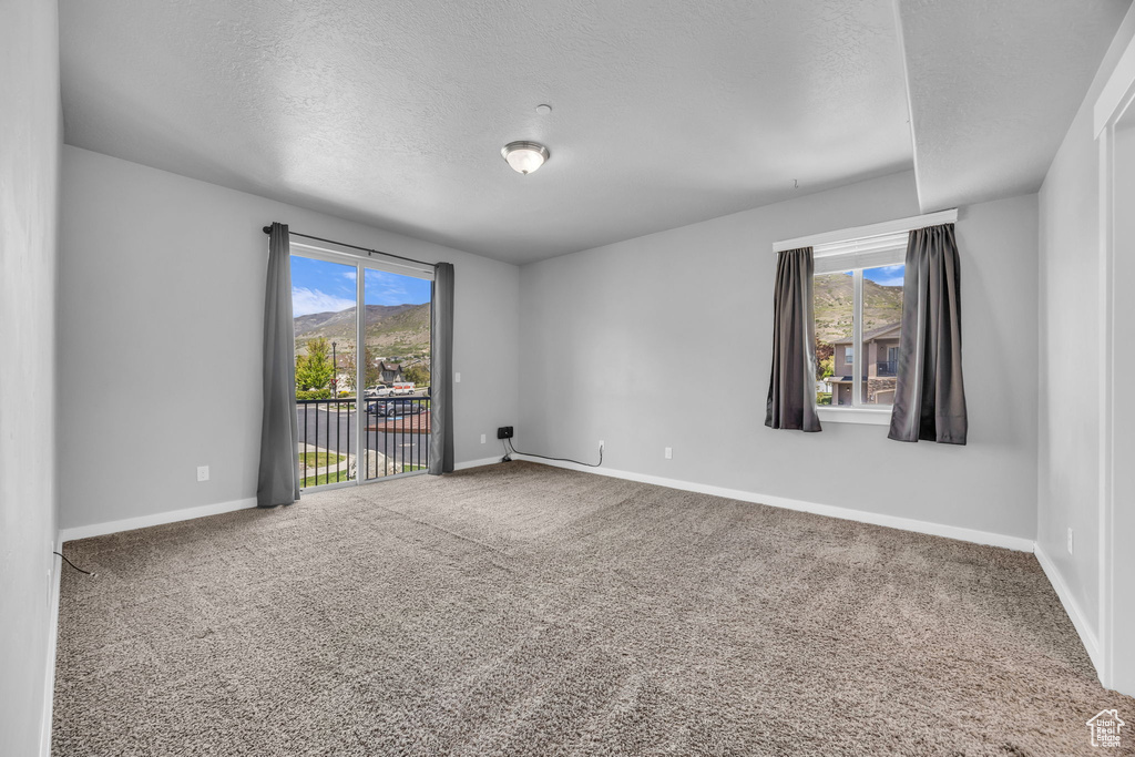 Unfurnished room with baseboards, a textured ceiling, and carpet