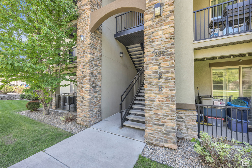 Entrance to property featuring stucco siding, stone siding, and a balcony