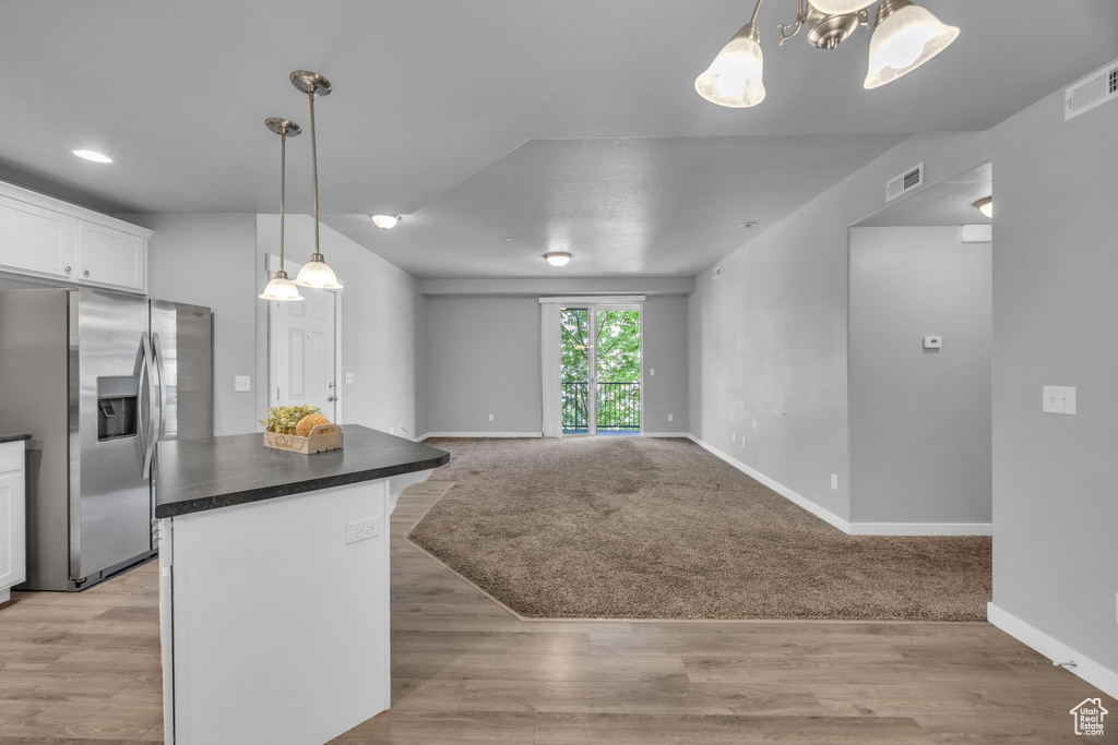 Kitchen featuring white cabinets, dark countertops, stainless steel fridge, and visible vents
