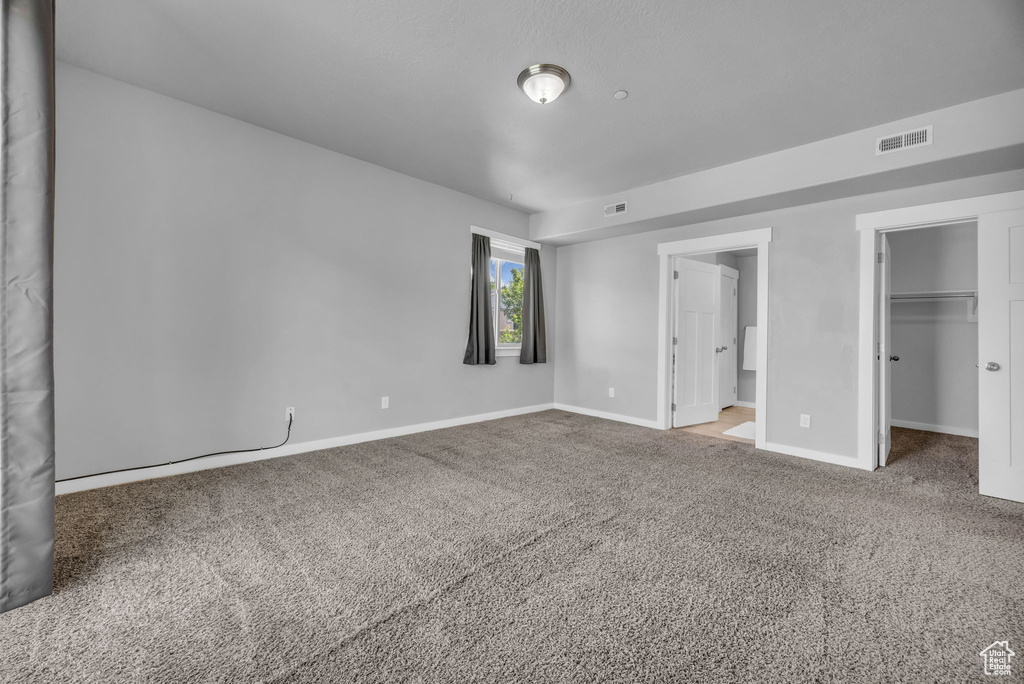 Unfurnished bedroom featuring baseboards, a spacious closet, visible vents, and carpet