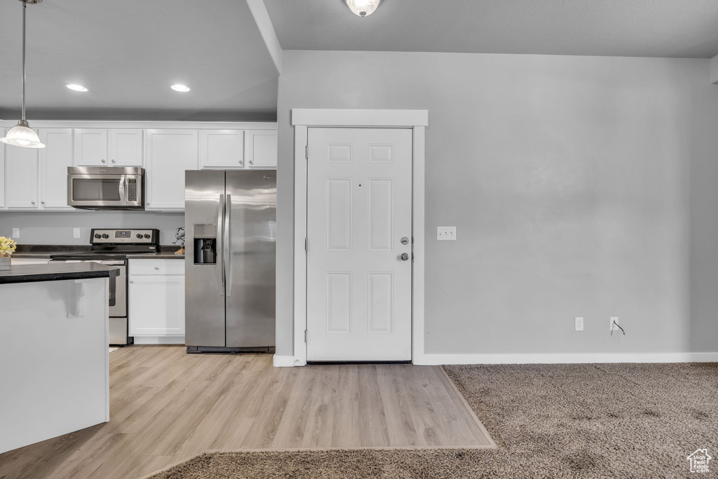 Kitchen with white cabinets, dark countertops, recessed lighting, and appliances with stainless steel finishes