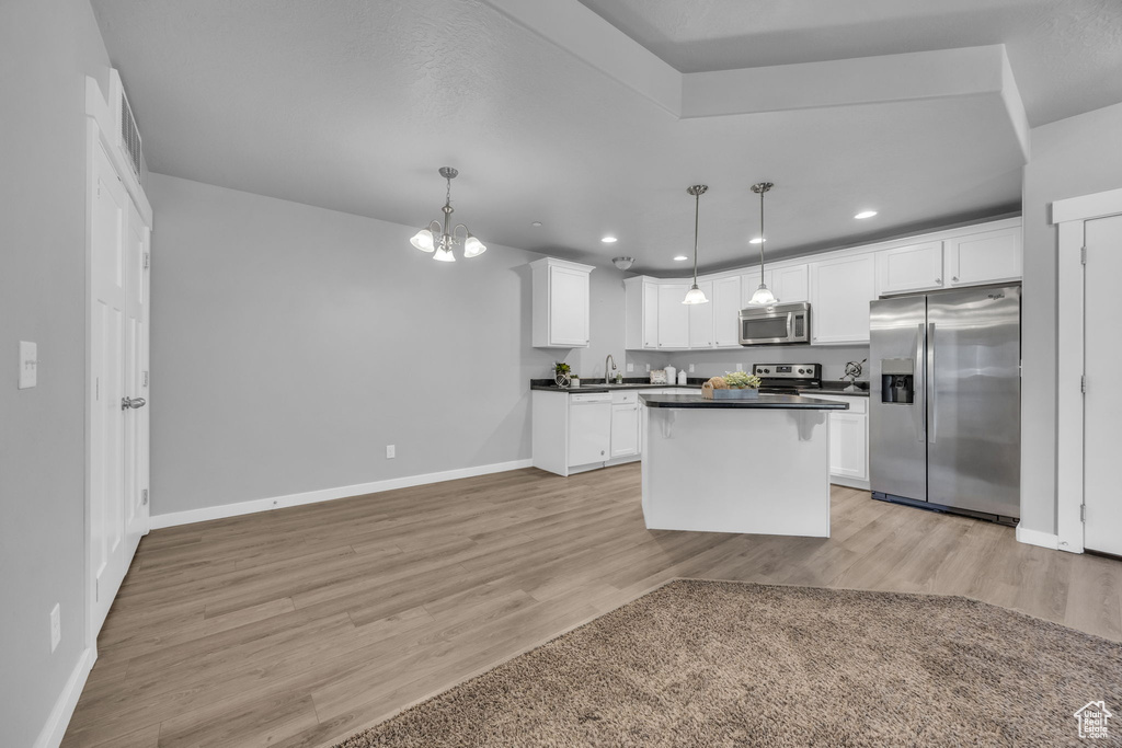 Kitchen with baseboards, light wood-style floors, dark countertops, stainless steel appliances, and white cabinets